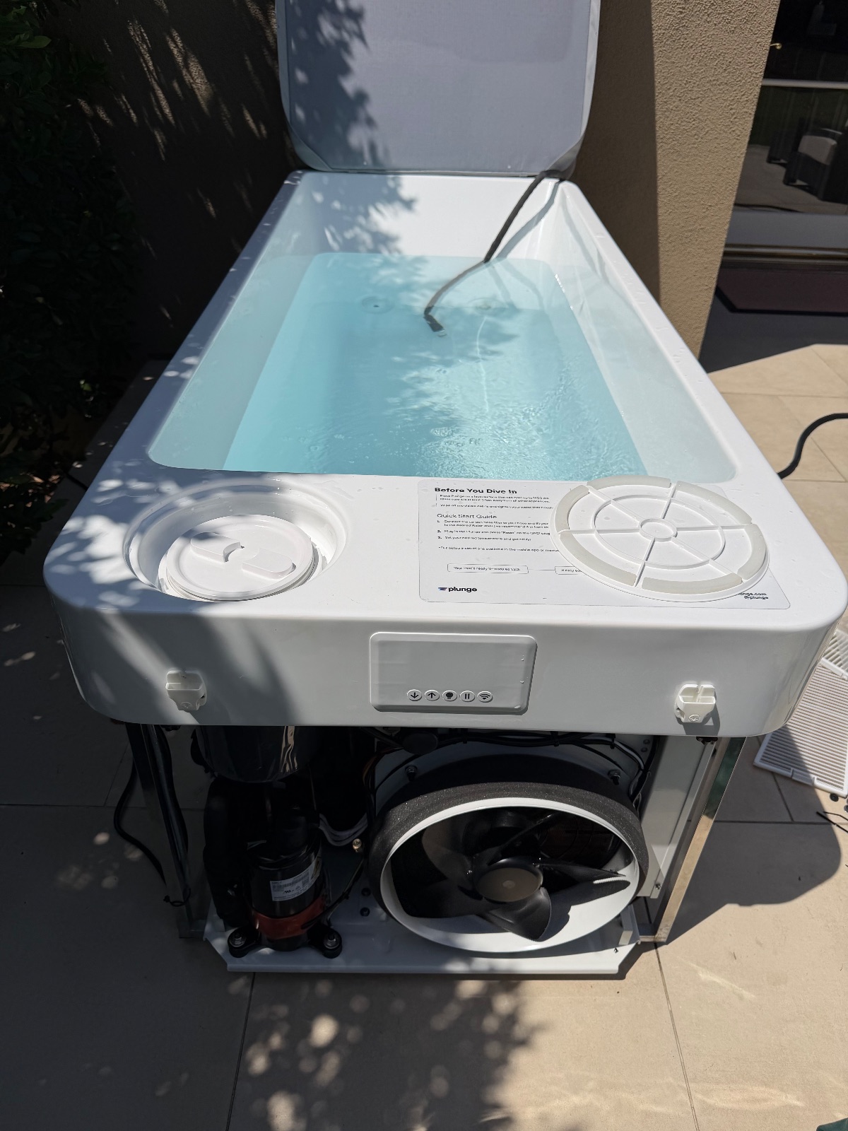 A cold plunge tub with the lid open, showing the chiller unit underneath
